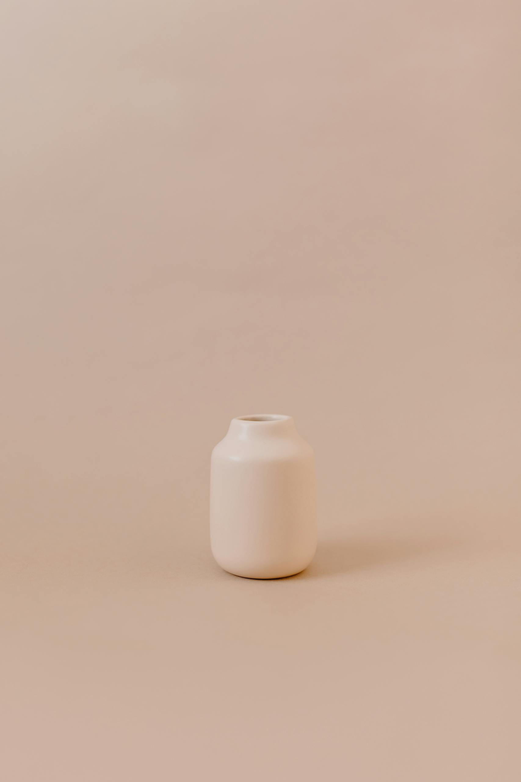 A simple ceramic pot with beige tones against a matching minimalist backdrop.